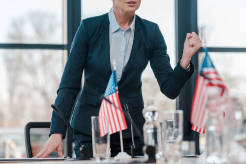 Cropped View Of Diplomat With Clenched Fist Talking While Standing Near Microphone And American