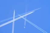 Many Distant Passenger Jet Planes Flying On High Altitude On Clear Blue Sky Leaving White Smoke Trace Of Contrail Behind Busy Air Transportation Concept