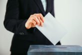Close Up Of Voter Putting Ballot Into Voting Box